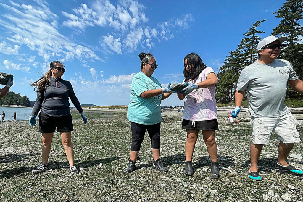 Kiarra Williams of La Conner passes a rock to her mother, Marcia Julius, at Kiket Island on Aug. 12. (John Ryan / KUOW)
