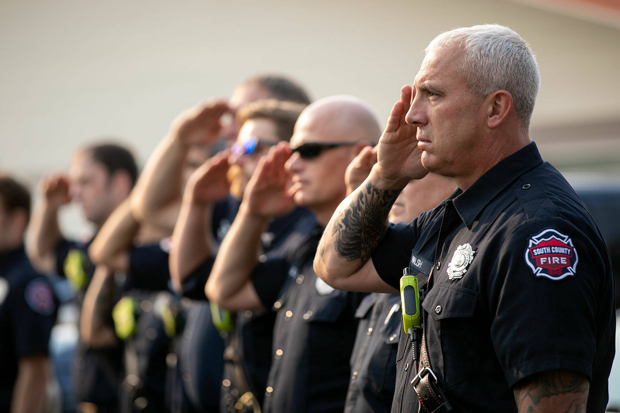 South County firefighters salute during the presentation of the colors during a ceremony to commemorate the 21st anniversary of the September 11 terrorist attacks on the U.S. on Sep. 11, 2022, outside South County Fire Station 17 in downtown Edmonds, Washington. (Ryan Berry / The Herald)