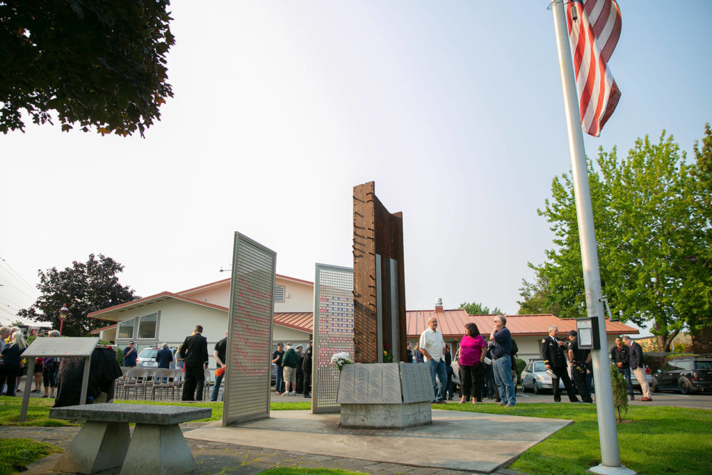 People talk amongst each other besides the Edmonds 9/11 memorial during a ceremony to commemorate the 21st anniversary of the September 11 terrorist attacks on the U.S. on Sep. 11, 2022, outside South County Fire Station 17 in downtown Edmonds, Washington. (Ryan Berry / The Herald)
