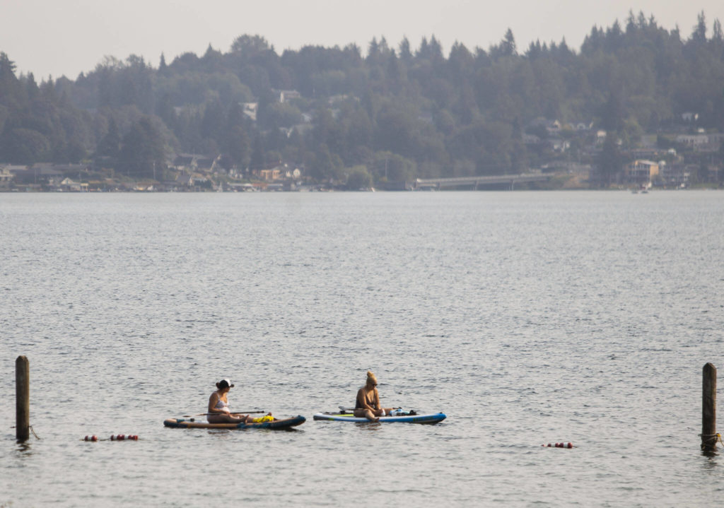 People sit on paddle boards out on Lake Stevens where smoke has settled on Friday, in Lake Stevens. (Olivia Vanni / The Herald)
