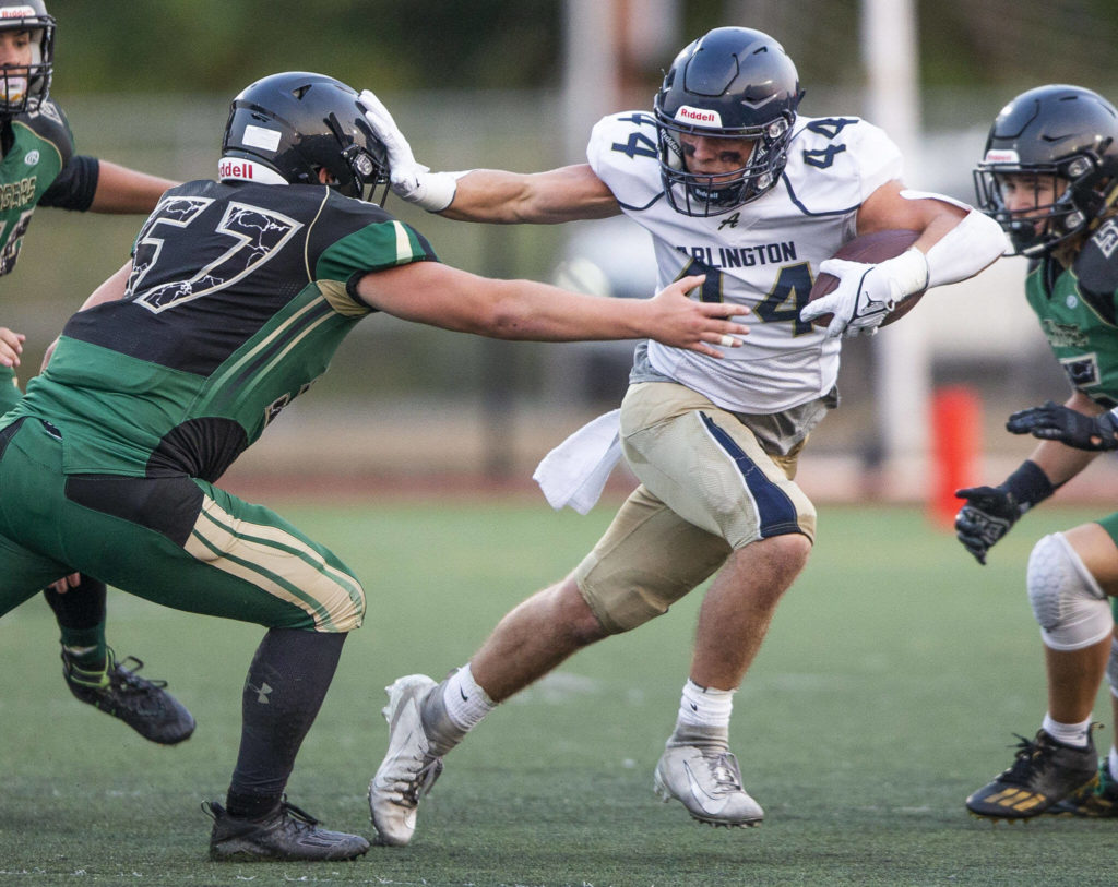 Arlington’s Spencer Fischer puts his arm out to block a tackle by Marysville Getchell’s Alexander Leach during the game on Friday, Sept. 9, 2022 in Marysville, Washington. (Olivia Vanni / The Herald)
