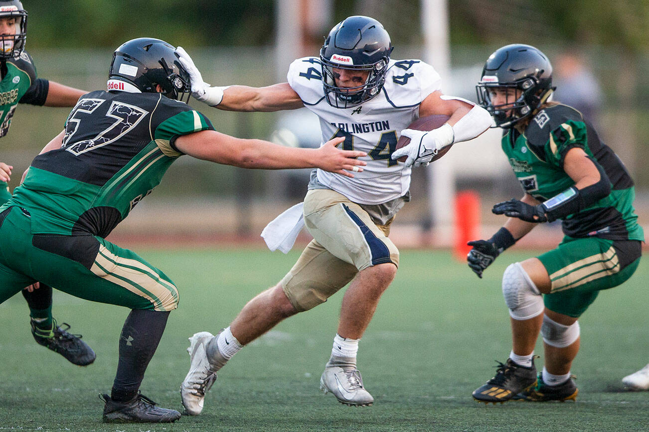 Arlington's Spencer Fischer puts his arm out to block a tackle by Marysville Getchell's Alexander Leach during the game on Friday, Sept. 9, 2022 in Marysville, Washington. (Olivia Vanni / The Herald)