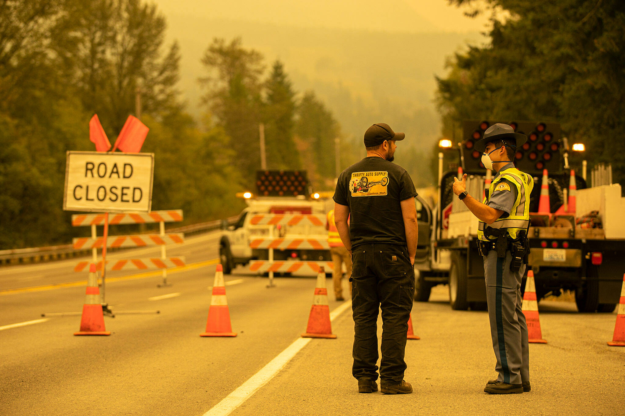 State Trooper Isaiah Oliver speaks to a BNSF worker at mile marker 31.7 as road closures and evacuations mount in response to the Bolt Creek Fire on Saturday, Sep. 10, 2022, on U.S. Highway 2 near Index, Washington. (Ryan Berry / The Herald)
