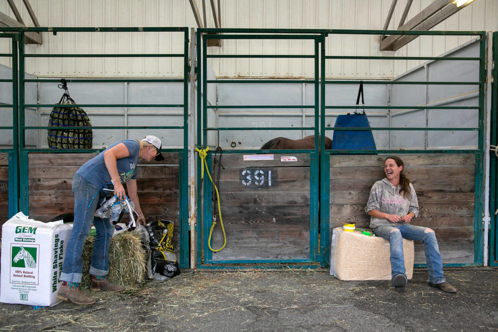 Doneatta Godinez and Nikki Prather, both of Gold Bar, take care of their horses at a stable on Sunday, Sep. 11, 2022, at the Evergreen State Fairgrounds in Monroe, Washington. Godinez brought 10 of her horses to the emergency stables at the fairgrounds in response to the Bolt Creek Fire, and Prather brought two. Both still have animals back on their properties near the site of the fire and are prepared to evacuate them as well if the flames moves closer. (Ryan Berry / The Herald)
