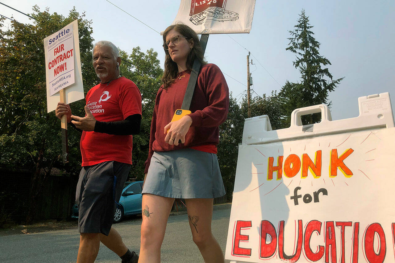 Guillermo Carvajal, a member of the support staff at Northgate Elementary School in Seattle, and Erin Carroll, an occupational therapist there, picket outside the building on the third day of a strike by the Seattle Education Association on, Sept. 9. The union and Seattle Public Schools continued negotiating over issued that include pay and support for special needs students. It remained unclear how long the strike might last. (AP Photo/Gene Johnson)