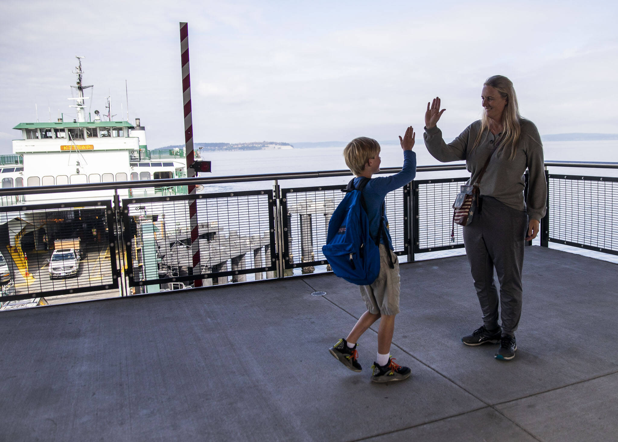 Genghin Carroll, 8, walks up and high fives his mom, Andria Carroll, after riding the ferry over to meet her for a dental appointment on Thursday, Mukilteo. (Olivia Vanni / The Herald)