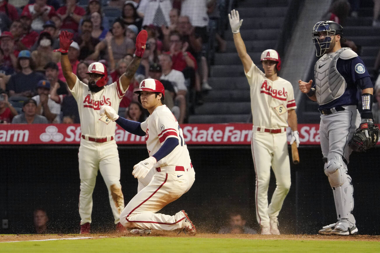 Los Angeles Angels' Shohei Ohtani, second from left, scores on a single by Taylor Ward as Luis Rengifo, left, and Matt Duffy, second from right, gestures while Seattle Mariners catcher Curt Casali watches during the first inning of a baseball game Friday, Sept. 16, 2022, in Anaheim, Calif. (AP Photo/Mark J. Terrill)