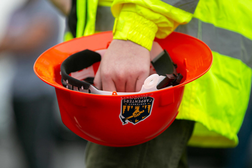A pre-apprentice holds a hardhat featuring the Northwest Caarpenters Union logo during the grand opening of the Northwest Carpenters Institute’s new building on Thursday, in Burlington. (Ryan Berry / The Herald)
