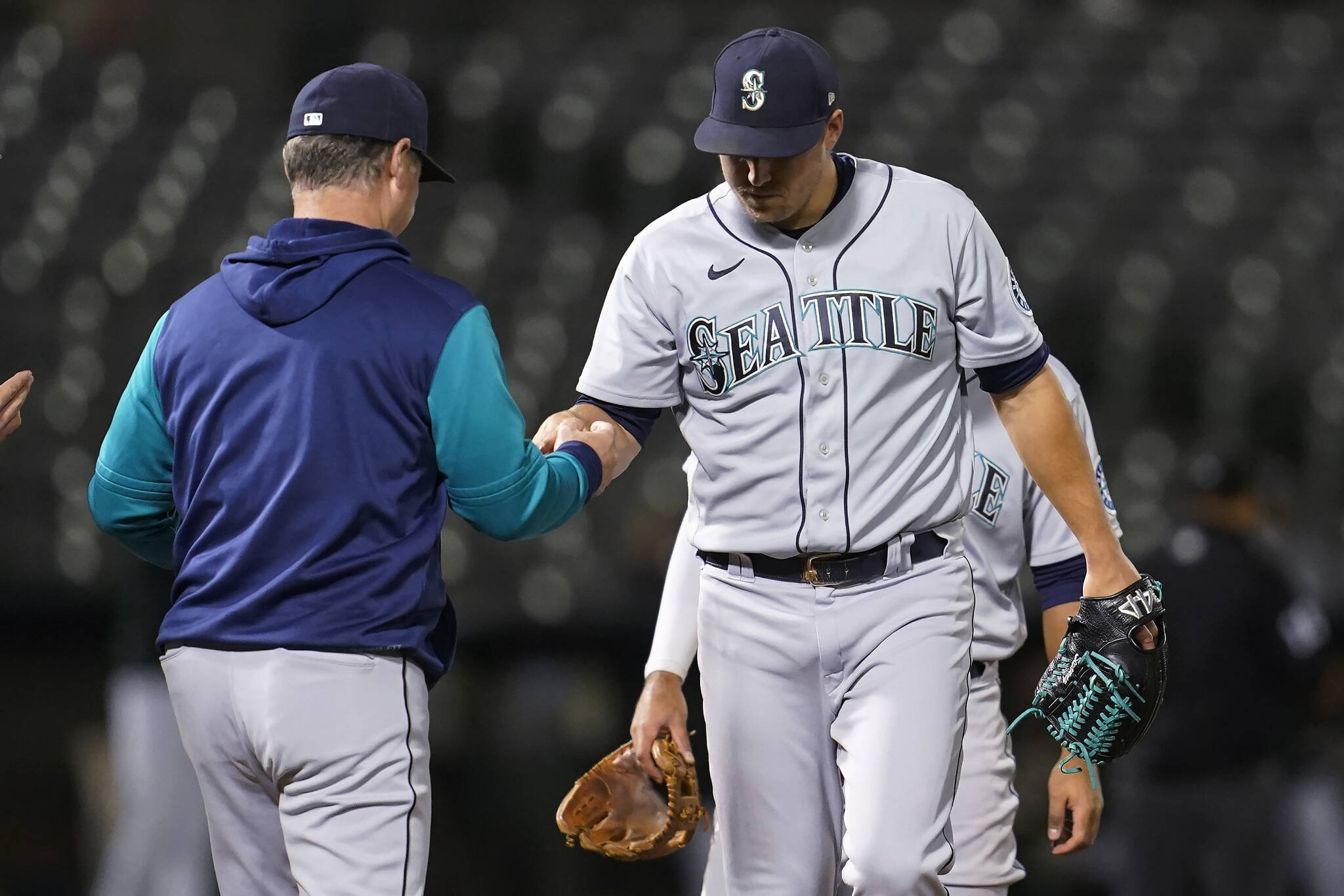 Mariners manager Scott Servais (left) takes the ball from pitcher Erik Swanson during the seventh inning of a game against the Athletics on Wednesday in Oakland, Calif. (AP Photo/Jeff Chiu)