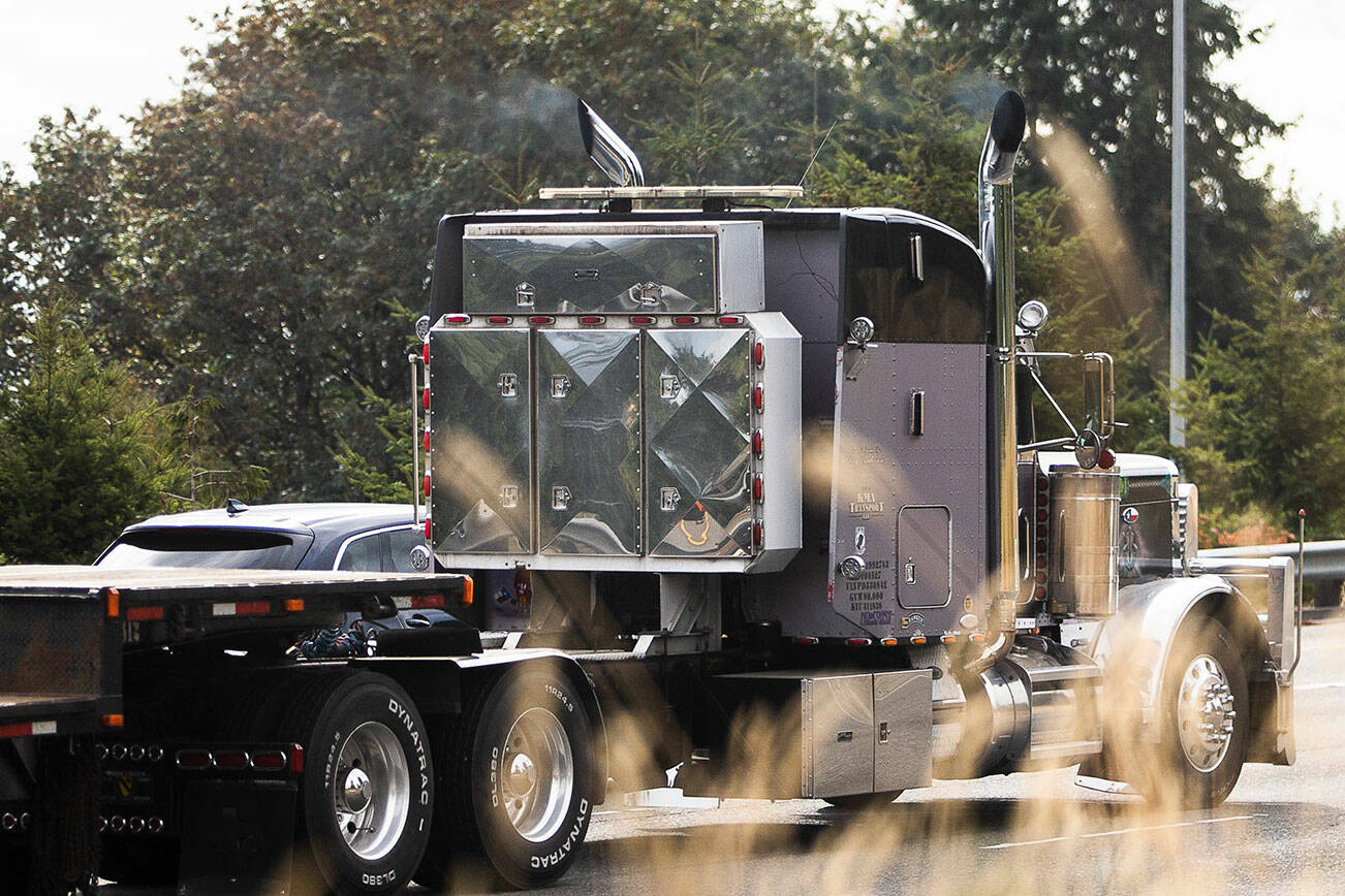 A semi truck blows smoke out of its exhaust pipes while driving southbound on I-5 on Friday, Sept. 23, 2022 in Everett, Washington. (Olivia Vanni / The Herald)