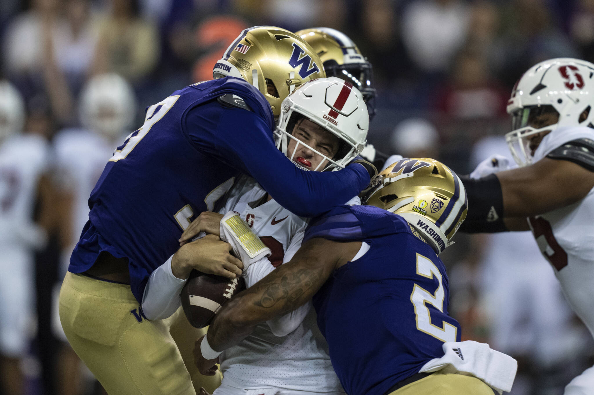 Washington’s Zion Tupuola-Fetui (left) and Cam Bright (right) sack Stanford quarterback Tanner McKee during the first half of a game Saturday night in Seattle. (AP Photo/Stephen Brashear)