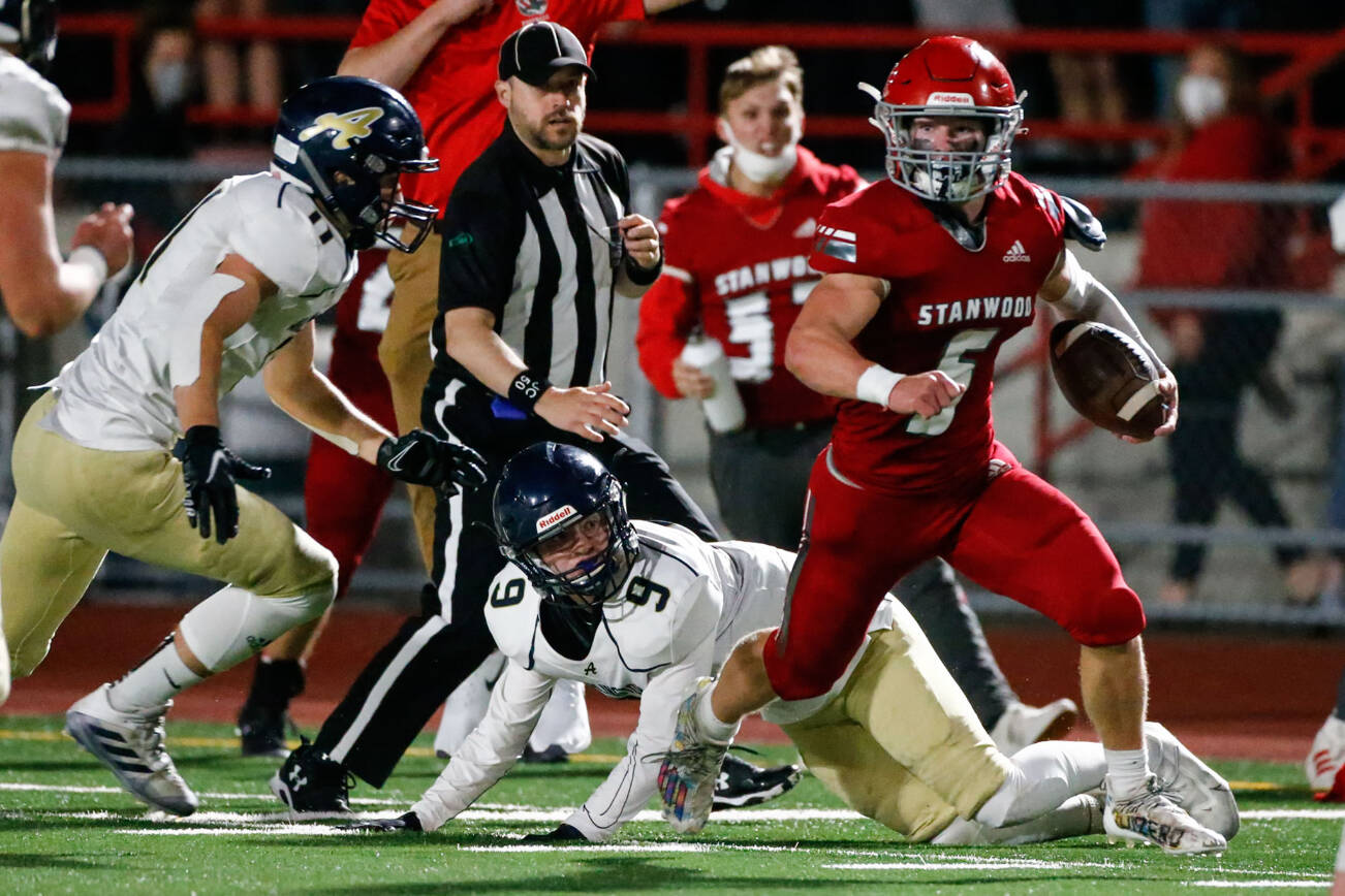 Stanwood's Ryder Bumgarner rushes with yardage with Arlington's Trenton Lamie, left, closing in the third quarter Friday night at Stanwood High School on September 24, 2021.  (Kevin Clark / The Herald)