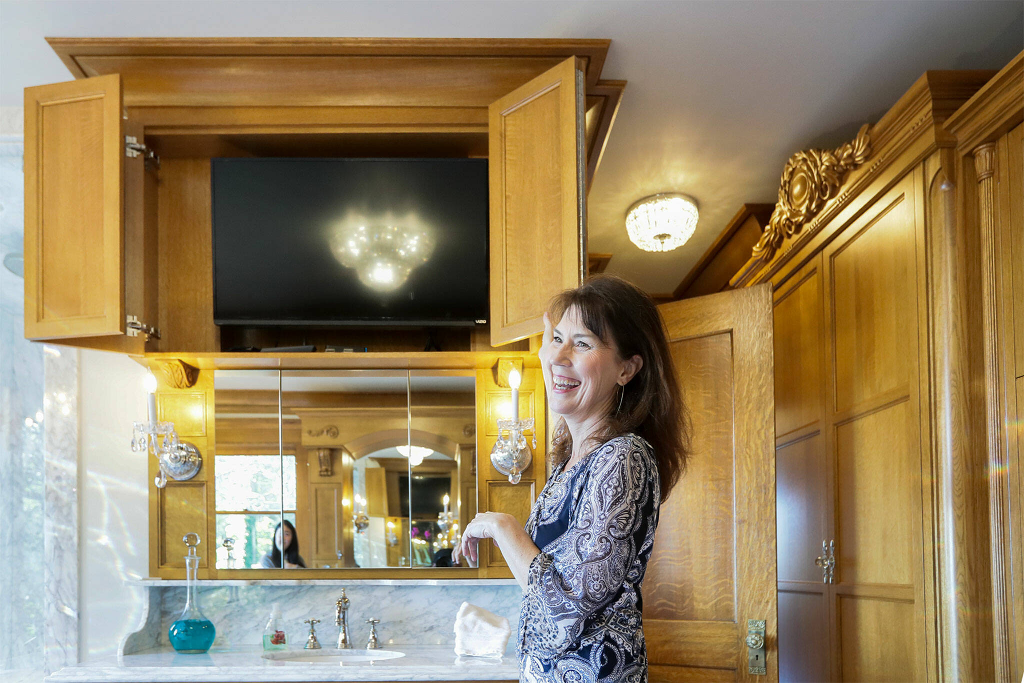 Brenda Kerr shows off her hidden television in the master bath at her home, the Rucker Mansion, on Oct. 11 in Everett. (Kevin Clark / The Herald)