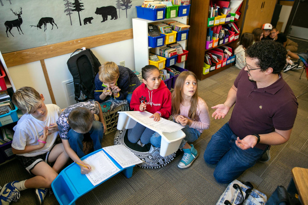 A group of fourth-grade students listen to teacher Zachary Pfrimmer explain what makes a complete sentence while working together on an assignment at Cedarhome Elementary on Sep. 21, in Stanwood. (Ryan Berry / The Herald) 
