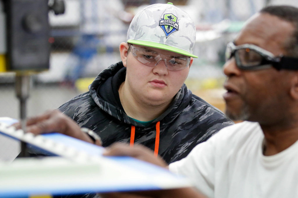 Asher Guillen watches as his mentor, Terry Pierce, rivets plane parts on Sept. 23, at Pathfinder Manufacturing in Everett. (Kevin Clark / The Herald)
