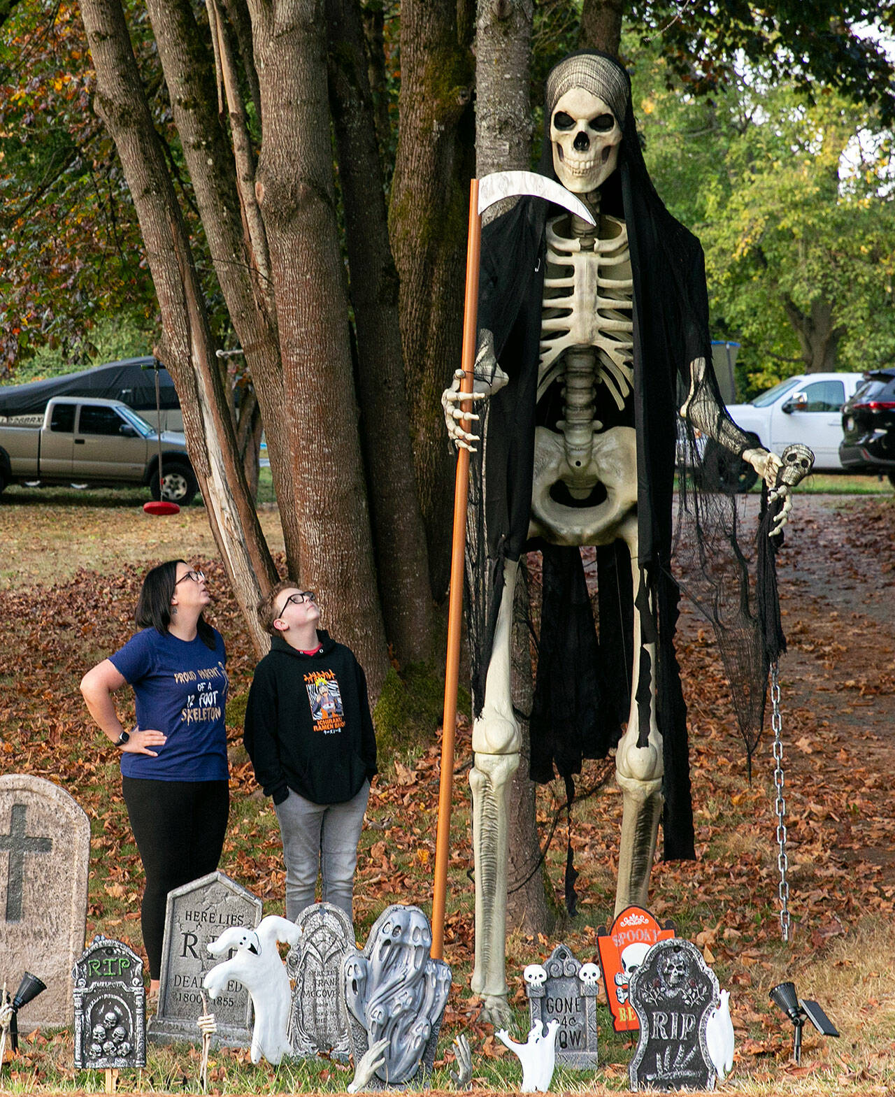 Jess Thomas and 11-year-old son Bentley look up at 12-foot Mr. Bone Jangles in their front yard in Lake Stevens. The Home Depot skeleton is a year-round fixture in the family’s yard, and is often seen sporting seasonal-appropriate attire. (Ryan Berry / The Herald)