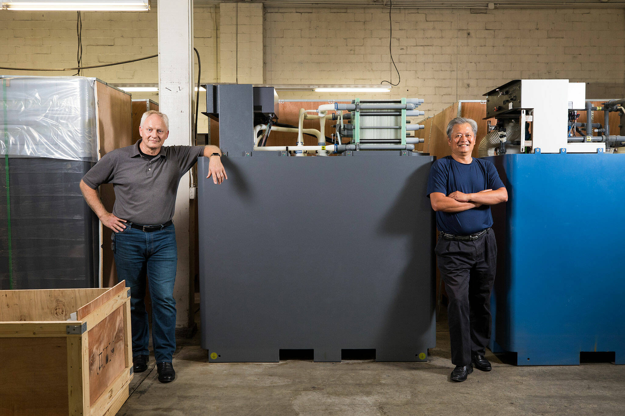 Rick Winter (left) and Gary Yang, the founders of the former UniEnergy Technologies, stand with one their latest batteries, the Reflex, on Aug. 10. (Dan DeLong / InvestigateWest)