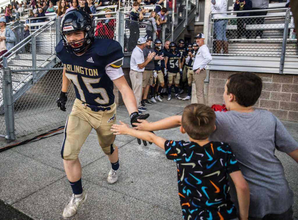 Arlington’s Dylan Scott gives high-fives as he runs onto the field before the Stilly Cup on Friday, Sept. 30, 2022 in Arlington, Washington. (Olivia Vanni / The Herald)
