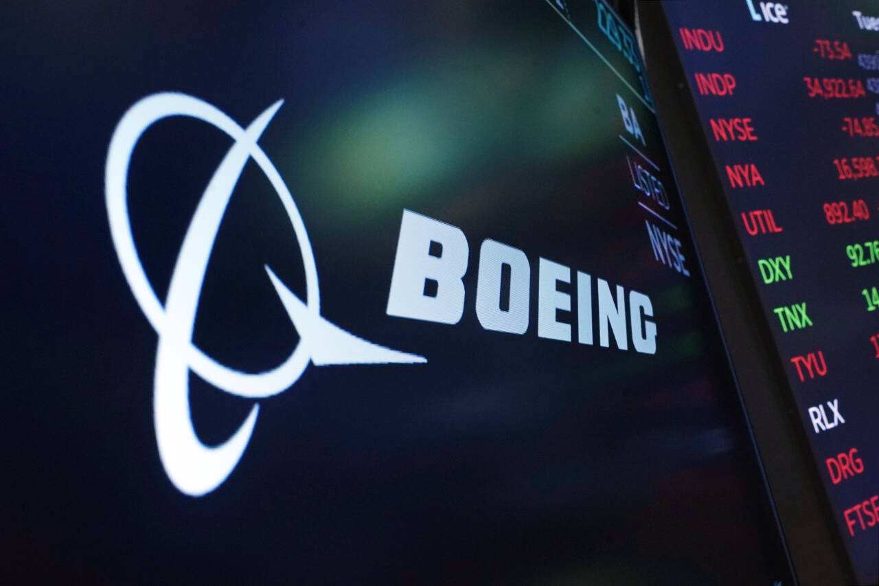 FILE - The logo for Boeing appears on a screen above a trading post on the floor of the New York Stock Exchange, Tuesday, July 13, 2021.  Boeing is behind schedule in submitting documentation for new versions of its 737 Max jetliner, and it's asking Congress for more time. Federal officials say Boeing has completed little of the work necessary to certify the new Max versions by a Dec. 31, 2022 deadline. (AP Photo/Richard Drew, file)