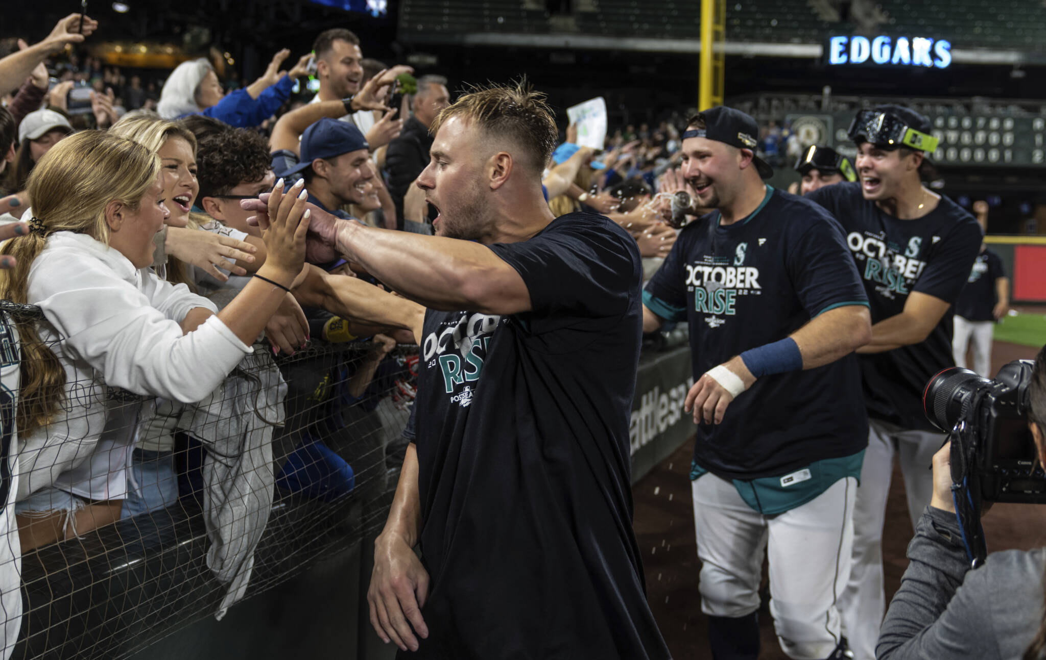 The Mariners’ Jarred Kelenic (front), Cal Raleigh (second from left) and others celebrate with fans after game against the Athletics on Friday in Seattle. (AP Photo/Stephen Brashear)