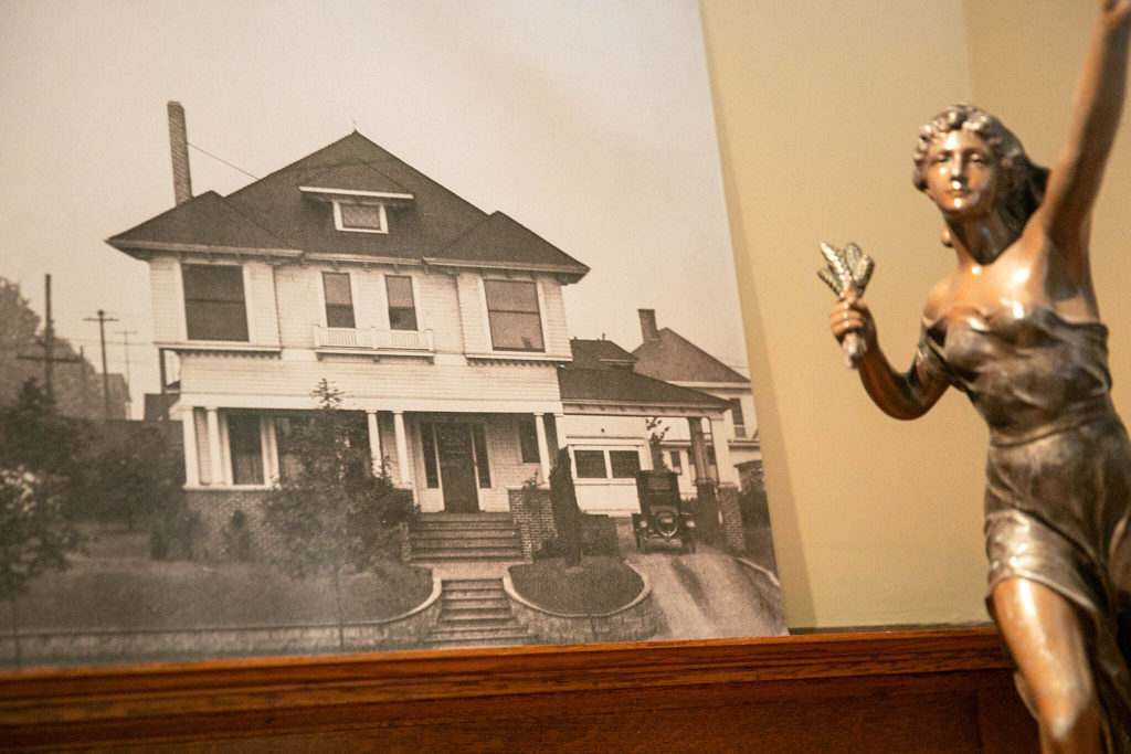 An old photo of the Van Valey House hangs on the wall next to the original lamp statue the Van Valey familyl had imported from France. (Ryan Berry / The Herald)
