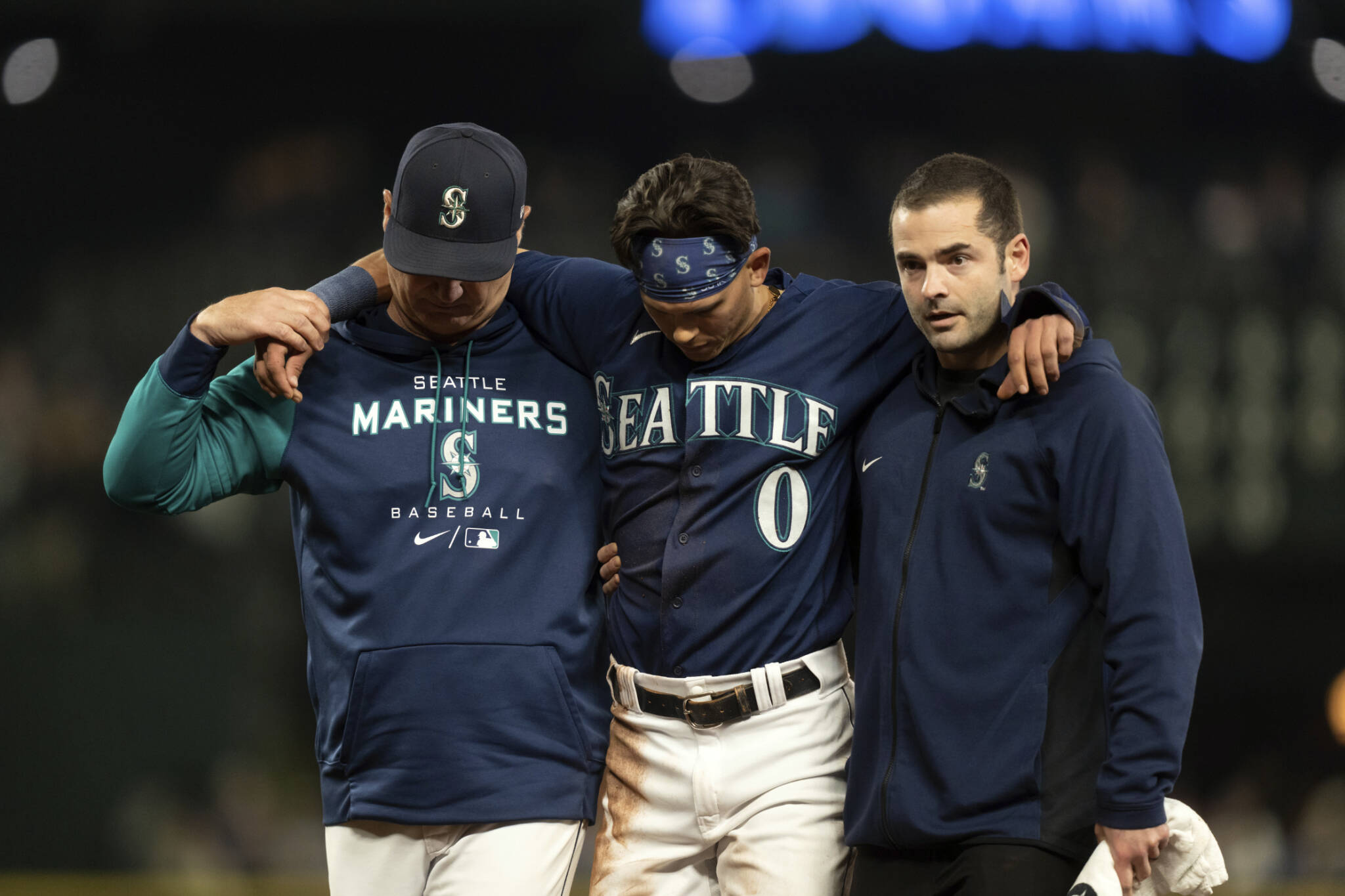 Seattle Mariners’ Sam Haggerty, center, is helped off the field by manager Scott Servais, left, and training personnel after stealing second base during the ninth inning of a game against the Detroit Tigers on Monday in Seattle. (AP Photo/Stephen Brashear)