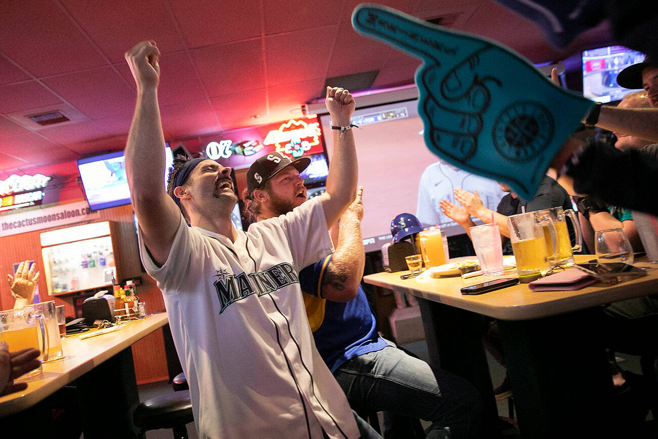 Kevin McLeod, 32, sporting his “Mariners moose-stache,” celebrates the Mariners’ fourth run of the day while watching Game 1 of their Wildcard matchup with the Toronto Blue Jays on Friday, Oct. 7, 2022, at Cactus Moon Saloon in Everett, Washington. (Ryan Berry / The Herald)