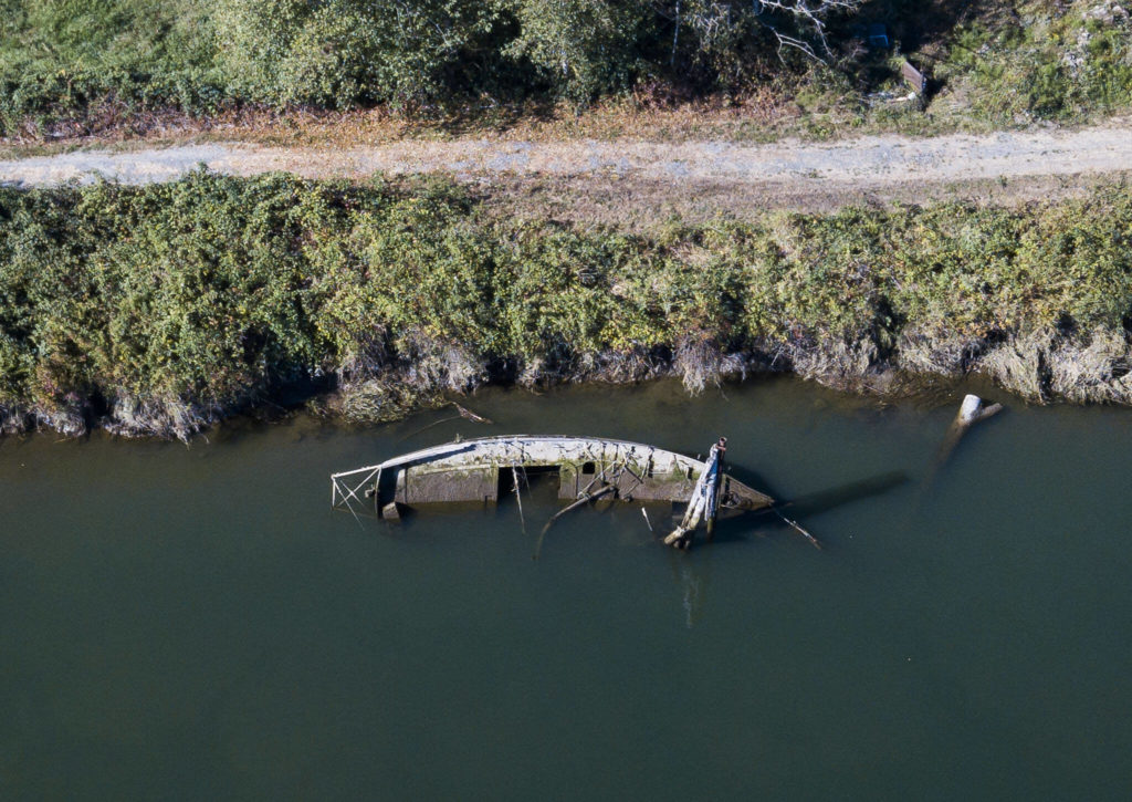 A derelict boat half underwater along the bank of Ebey Slough on Tuesday, in Everett. (Olivia Vanni / The Herald)
