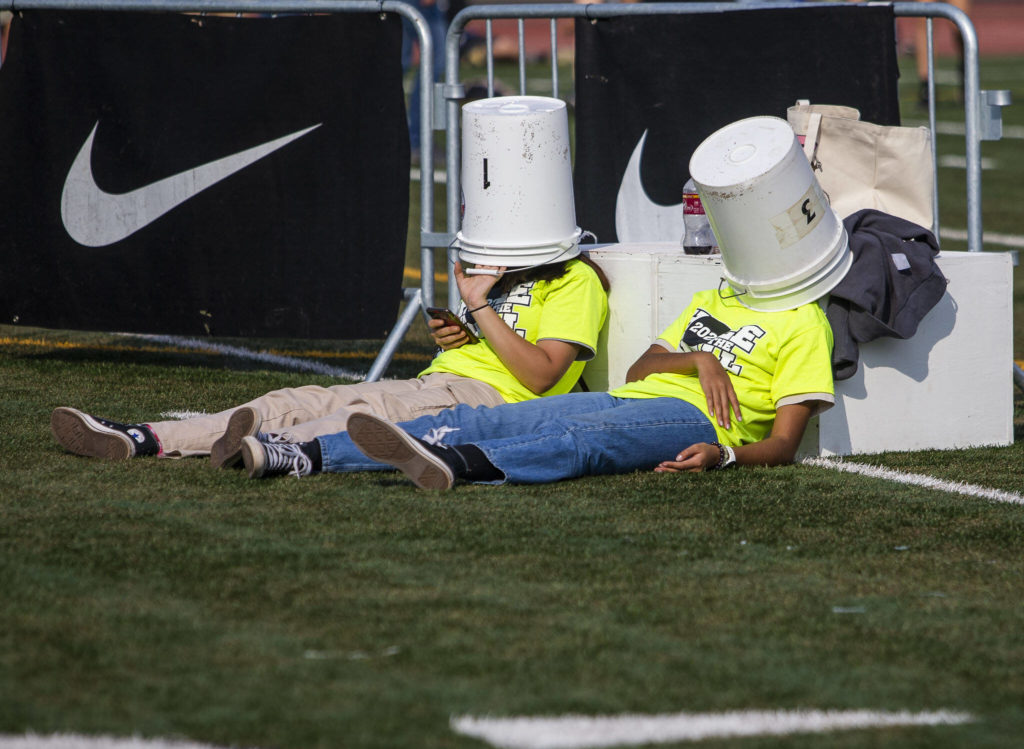 Volunteers wait under buckets between races at the Hole In The Wall Invitational on Saturday, Oct. 8, 2022 in Arlington, Washington. (Olivia Vanni / The Herald)
