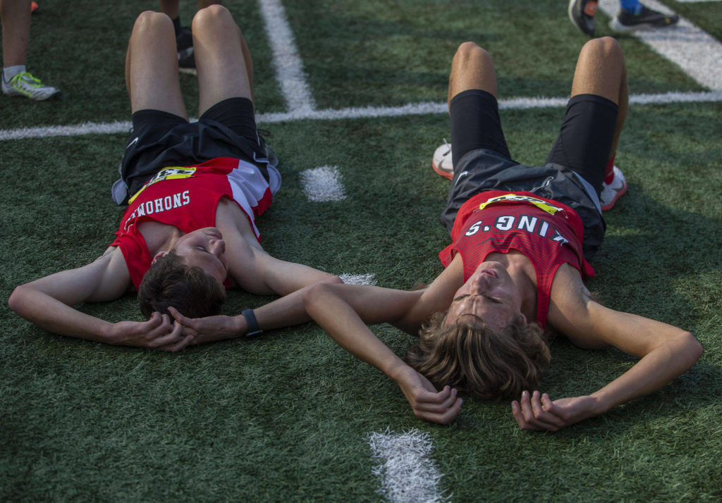 A Snohomish and Kings runner lay on the ground after their race at the Hole In The Wall Invitational on Saturday, Oct. 8, 2022 in Arlington, Washington. (Olivia Vanni / The Herald)
