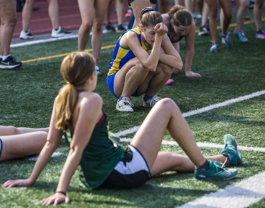 Runners falls and lie on the turf after finishing their race at the Hole In The Wall Invitational on Saturday, Oct. 8, 2022 in Arlington, Washington. (Olivia Vanni / The Herald)
