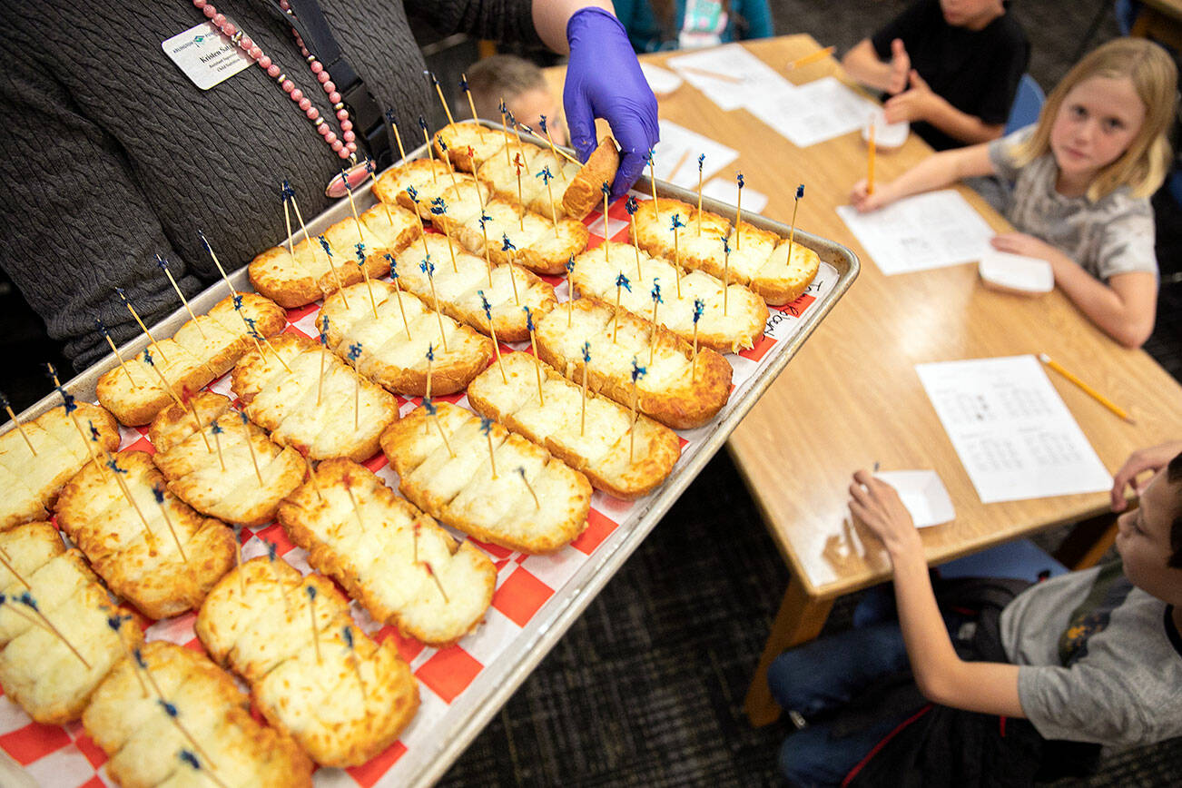 A tray of garlic bread gets distributed to third graders during a tasting event Tuesday, Oct.11, 2022, at Eagle Creek Elementary in Arlington, Washington. (Ryan Berry / The Herald)
