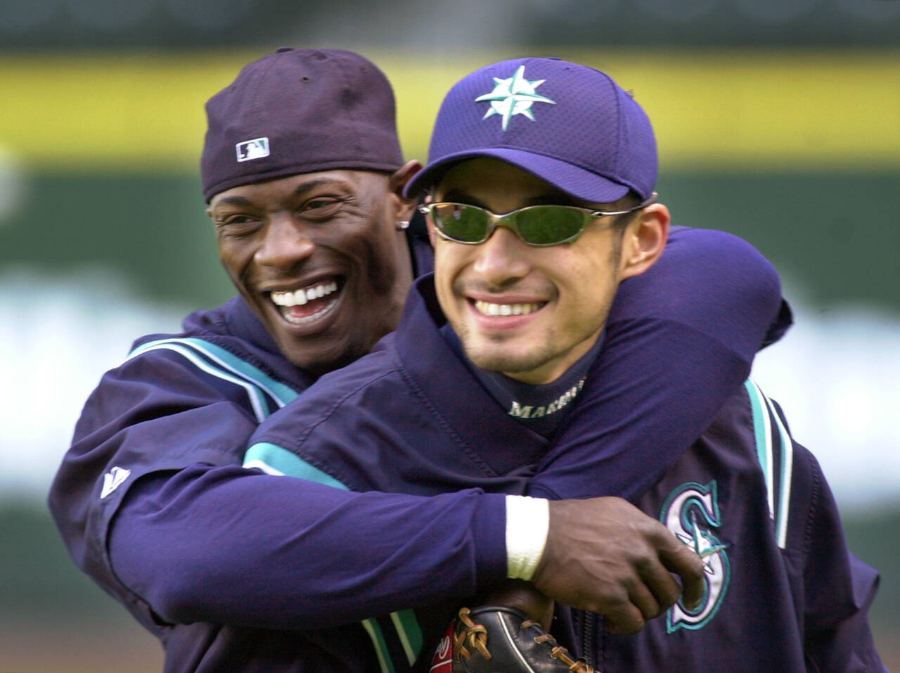 The Mariners’ Mike Cameron (left) embraces teammate Ichiro Suzuki during a workout on Oct. 8, 2001, in Seattle. After a 21-year absence, the postseason is back in Seattle for Game 3 of the ALDS against Houston on Saturday. (AP Photo/Elaine Thompson)