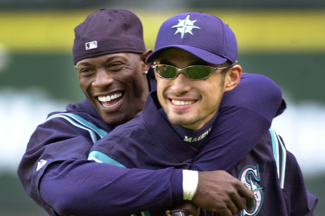 FILE - Seattle Mariners' Mike Cameron, left, embraces teammate Ichiro Suzuki during their workout Monday, Oct. 8, 2001, in Seattle. An entire generation has waited for the Seattle Mariners to bring playoff baseball back to the Pacific Northwest. After a 21-year absence, the postseason is back in Seattle for Game 3 of the ALDS against Houston. (AP Photo/Elaine Thompson, File)