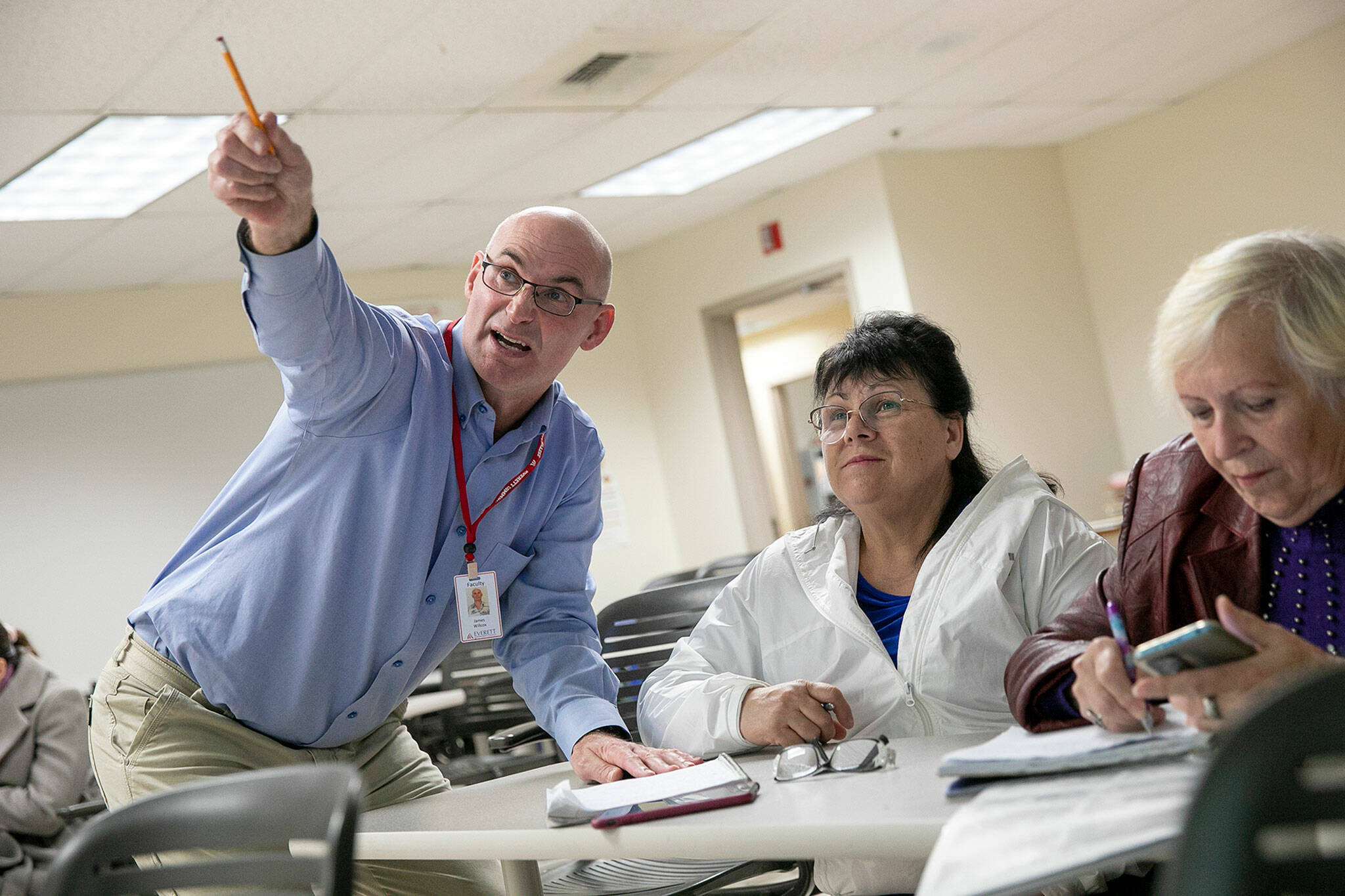 Senior Associate Professor James Willcox goes around the class and helps students answer questions about the present continuous verb tense in an ESL class at Everett Community College on Monday, in Everett. (Ryan Berry / The Herald)