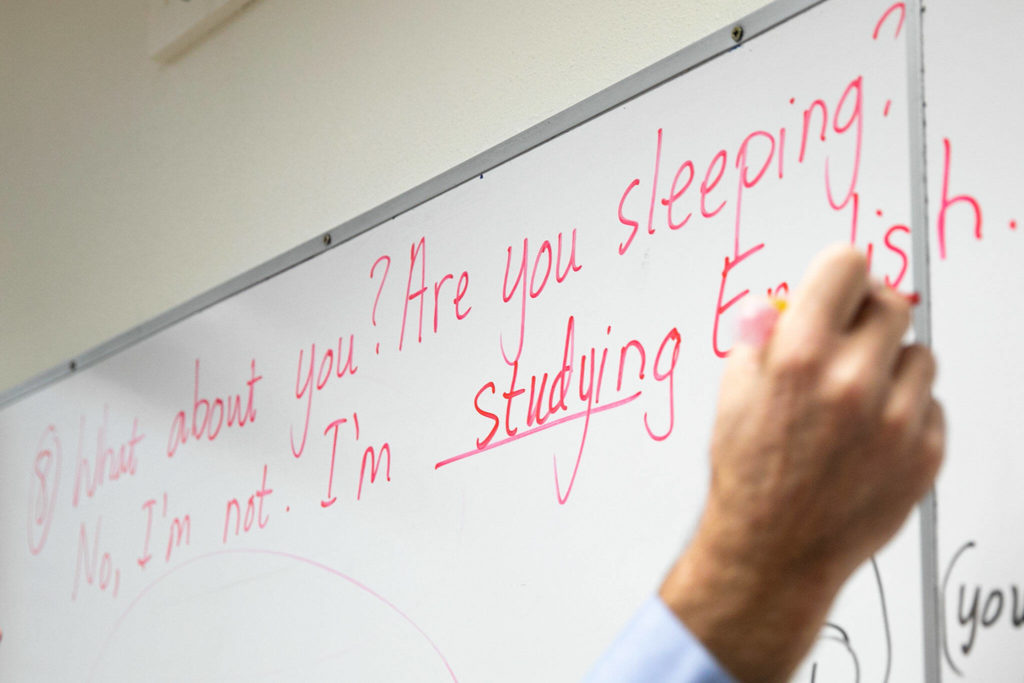 Senior Associate Professor James Willcox fills out a sentence on the whiteboard during an ESL class at Everett Community College on Monday, in Everett. (Ryan Berry / The Herald)
