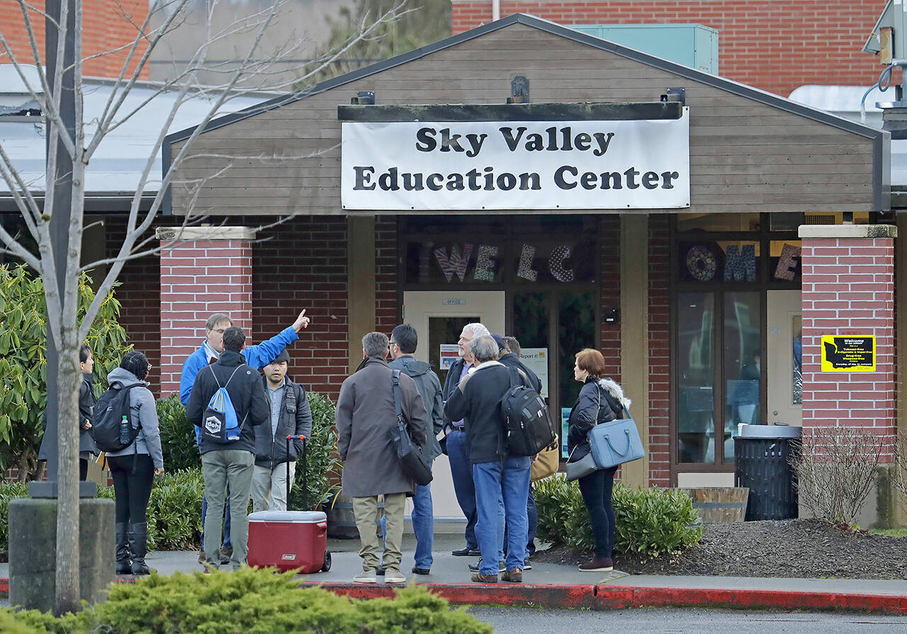 In this Jan. 4, 2019 photo, workers and other officials gather outside the Sky Valley Education Center school in Monroe, Wash., before going inside to collect samples for testing. The samples were tested for PCBs, or polychlorinated biphenyls, as well as dioxins and furans. A lawsuit filed on behalf of several families and teachers claims that officials failed to adequately respond to PCBs, or polychlorinated biphenyls, in the school. (AP Photo / Ted S. Warren)