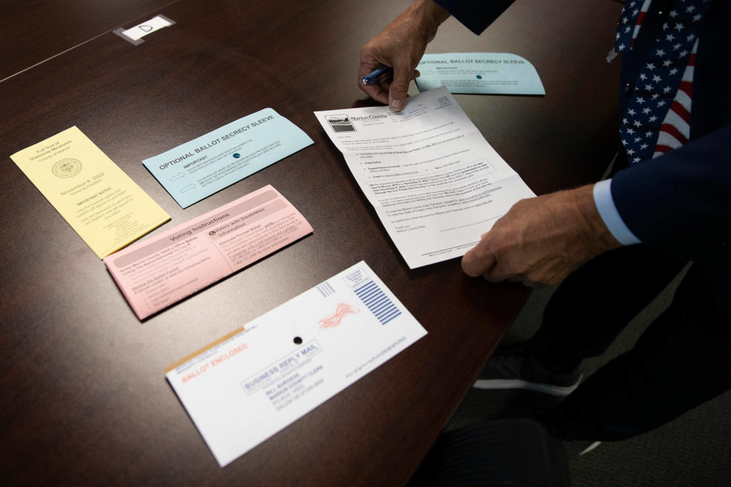 Bill Burgess, Marion County Clerk, lays out sample materials that would be included in a military and out of country ballot on Sept. 28, at the Marion County Clerk’s Office. (Amanda Loman / InvestigateWest)
