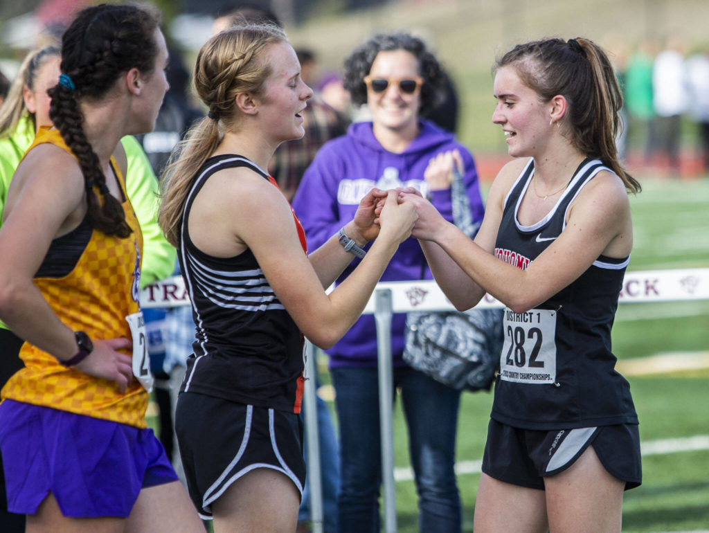 Snohomish’s Paige Gerrard, right, fist bumps Monroe’s Alexis Canovali-McKenzie who finished fourth during the 3A Girls District Cross Country championship race on Saturday, Oct. 29, 2022 in Arlington, Washington. (Olivia Vanni / The Herald)
