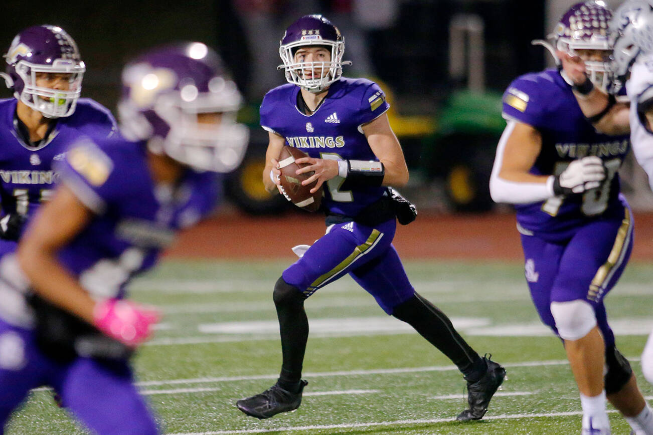 Lake Stevens’ Kolton Matson rolls out of the pocket behind his line while looking to throw downfield against Glacier Peak on Friday, Oct. 28, 2022, at Lake Stevens High School in Lake Stevens, Washington. (Ryan Berry / The Herald)