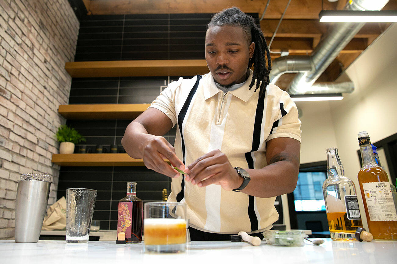 Nigel Lindsey of Revolution by the Barrel adds a sage leaf garnish to his spin on a New York sour while demonstrating his mobile cocktail service Sunday, Nov. 6, 2022, at Think Tank Cowork in Everett, Washington. (Ryan Berry / The Herald)