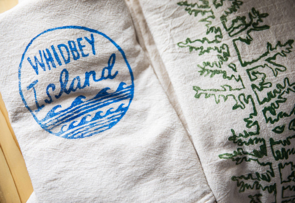 Screen-printed dish towels at Madrona Supply Co., which specializes in homemade screen-printed apparel and high-quality wooden kitchen and home items made by its sister company, Turnco Wood Products. (Olivia Vanni / The Herald)
