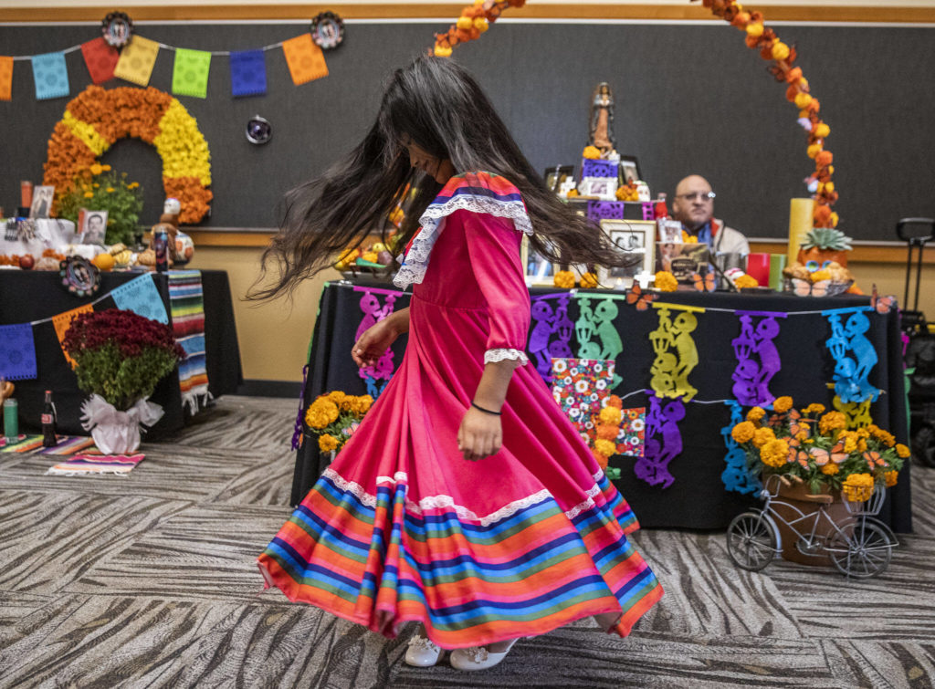 Belinda Reyes-Ordoñez, 7, spins in her dress while looking at the different ofrendas at the Washington-Guerrero Foundation’s Día de los Muertos event at the Lynnwood Convention Center on Saturday, in Lynnwood. (Olivia Vanni / The Herald)
