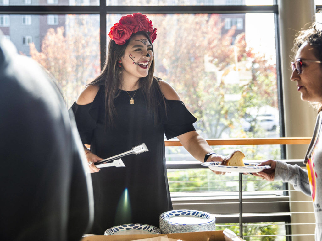 Daniela Altamirano-Crosby smiles while serving Pan de Muertos at the Washington-Guerrero Foundation’s Día de los Muertos event at the Lynnwood Convention Center on Saturday, in Lynnwood. (Olivia Vanni / The Herald)
