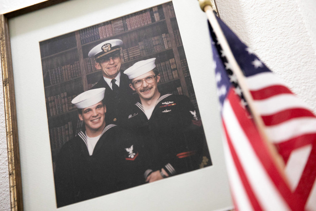 A photo of Russ Hupe and his two sons hangs outside Hupe’s home on Nov. 3, at Cogir Senior Living in Mill Creek. (Ryan Berry / The Herald)
