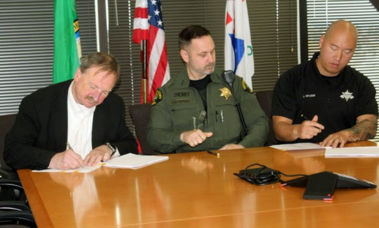 Snohomish County Executive Dave Somers, left, Sheriff Adam Fortney and Deputy Sheriffs Association President Jonathan Krajcar sign a new contract between Snohomish County and the Snohomish County Deputy Sheriff’s Association on Nov. 2. (Snohomish County)