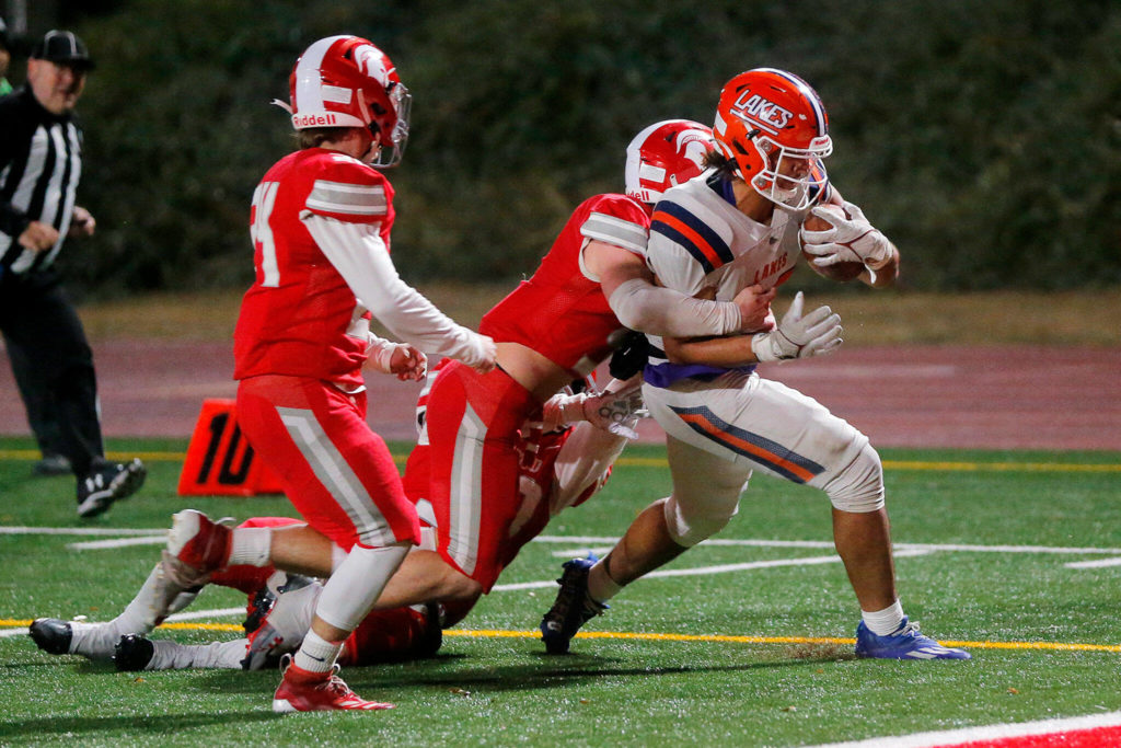 Lakes High School’s Leo Pulalasi carries a defender into the end zone for a score against Stanwood on Friday, Nov. 4, 2022, at Stanwood High School in Stanwood, Washington. (Ryan Berry / The Herald)
