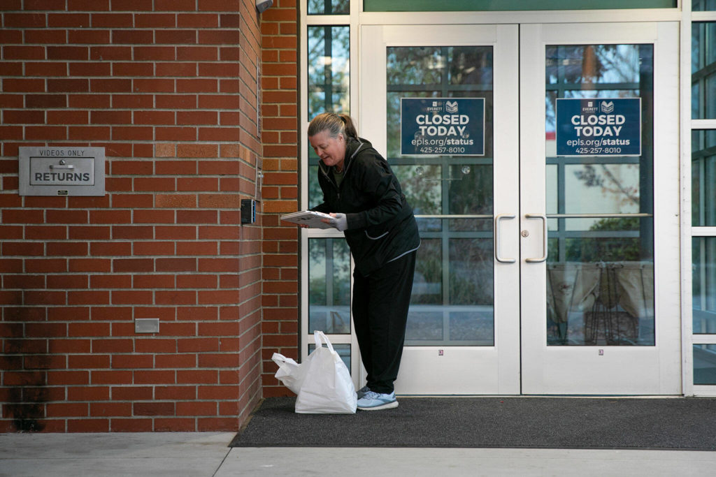 Maureen Polk, of Mukilteo, returns a stack of books to the Evergreen Branch of the Everett Public Library on Friday, in Everett. Polk said she uses the Evergreen Branch for returns since it’s closer to her home than the downtown location. (Ryan Berry / The Herald)
