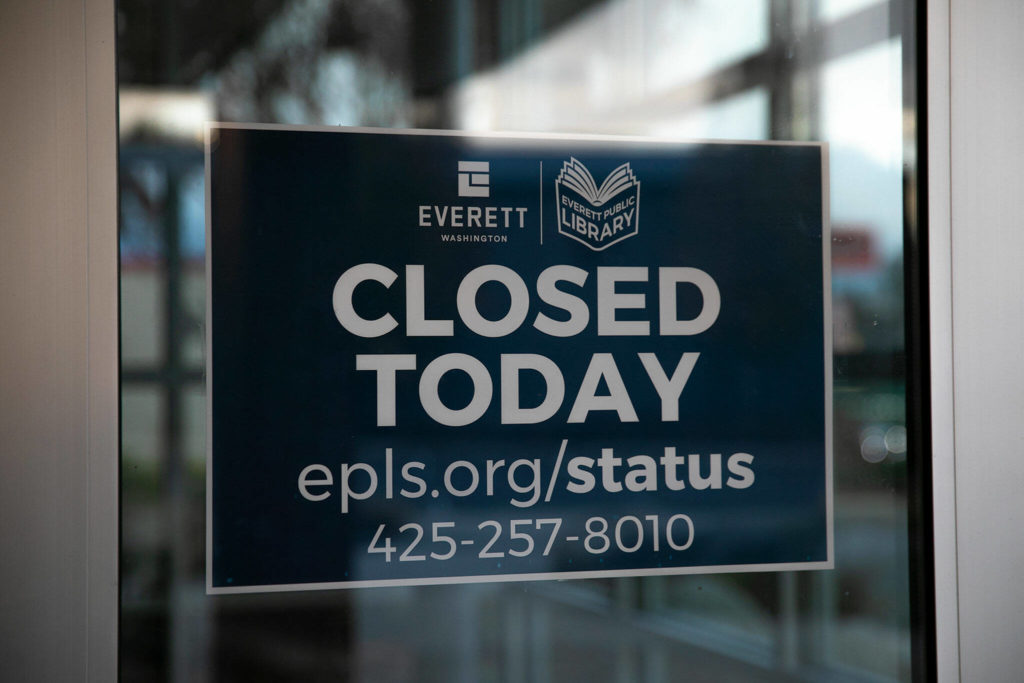 A closed sign is posted inside the front doors at the Evergreen Branch of the Everett Public Library on Friday, in Everett. (Ryan Berry / The Herald)
