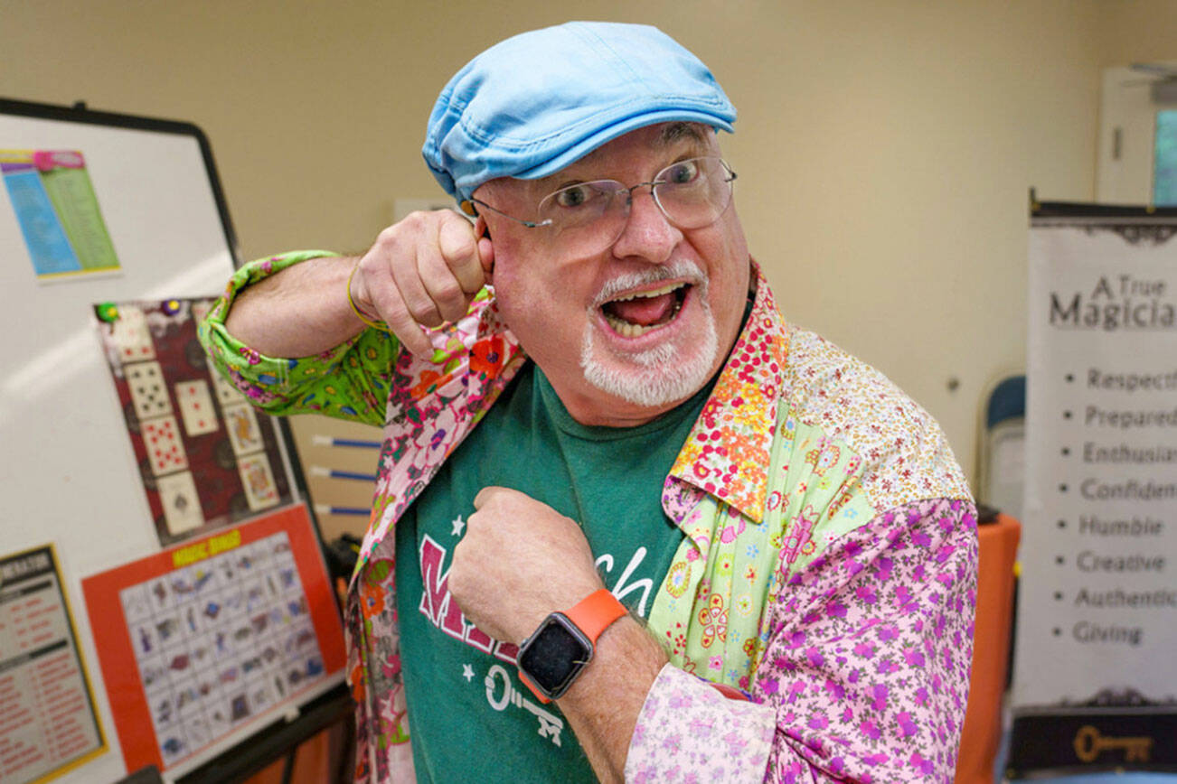 Magician JR Russell attempts to pull something out of his ear. For the past eight years, Russell has been teaching magic to kids with a side of life skills. (David Welton)